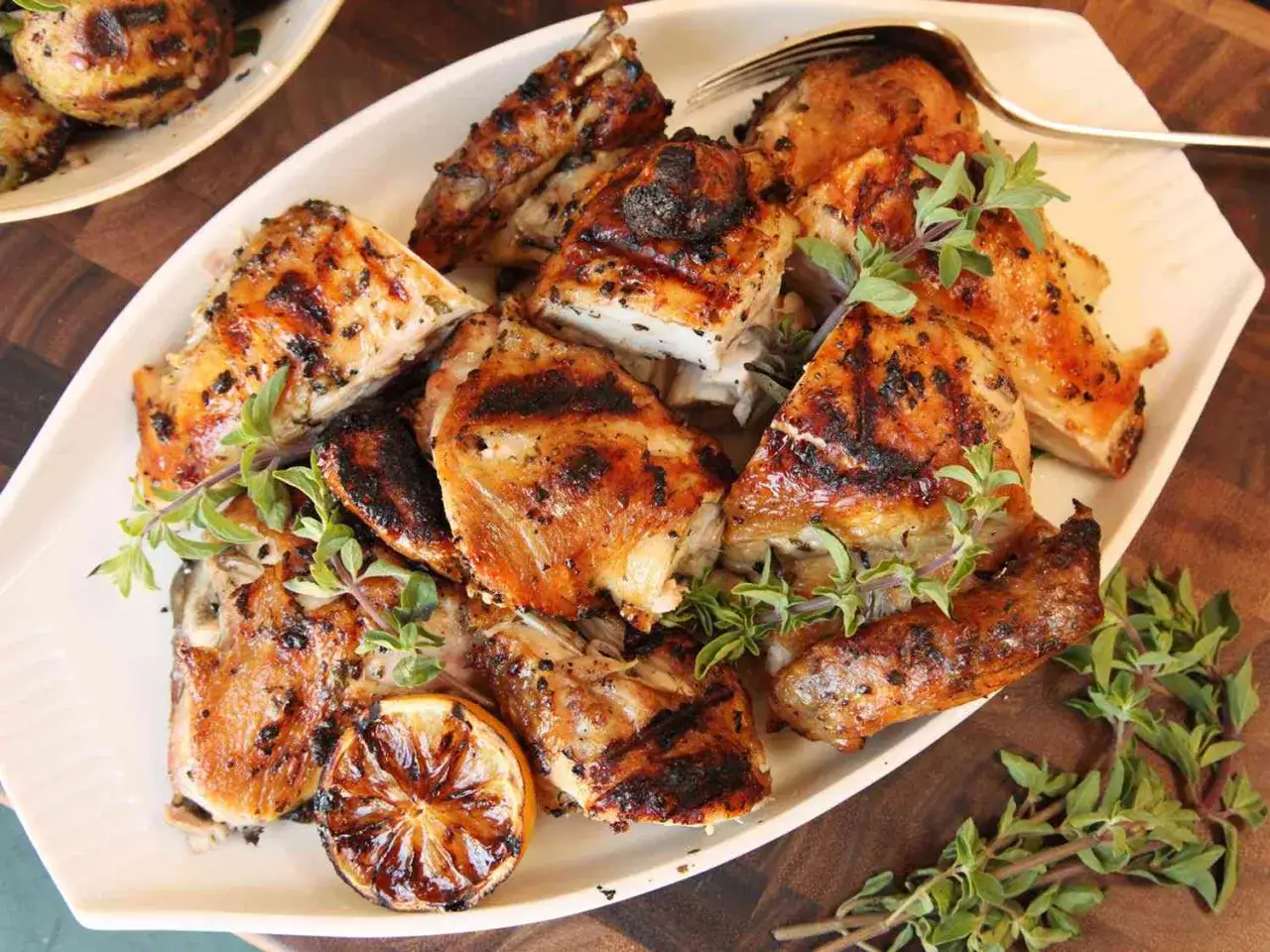 Saftiges, gegrilltes H&auml;hnchen, perfekt f&uuml;r pollo fino rezepte. Mit frischen Kr&auml;utern und gegrillter Zitrone garniert.