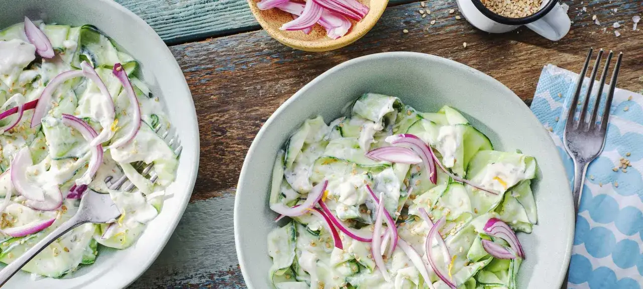 Erfrischender Gurkensalat mit cremiger Soße und roten Zwiebeln. Ein leichtes Gericht, das sich perfekt für sommerliche Rezepte mit Gurken eignet.