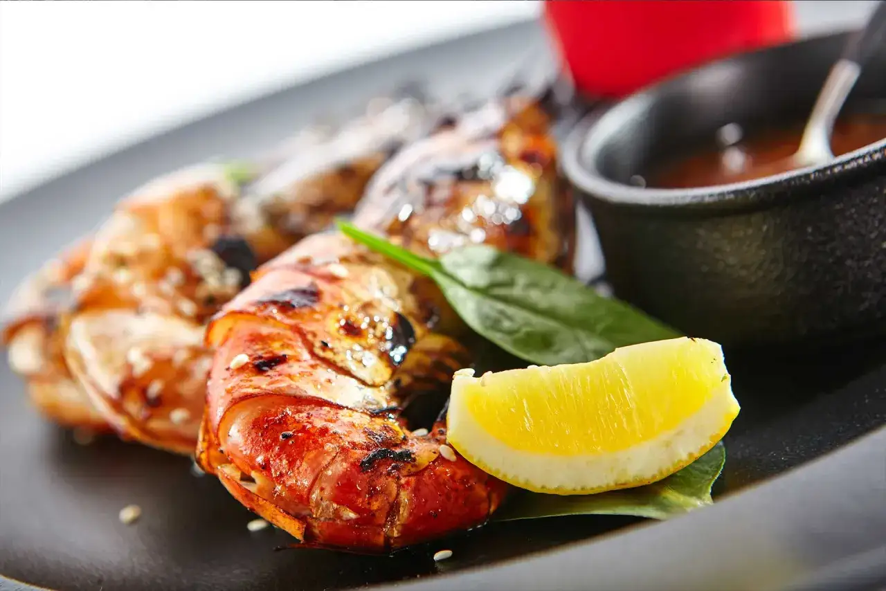 Saftige black tiger garnelen grillen, garniert mit Zitrone und einem Dip.