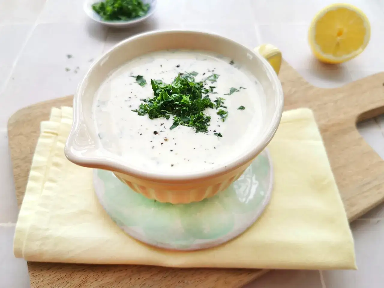 Cremiger ranch dressing, garniert mit frischer Petersilie und Pfeffer, serviert in einer Sch&uuml;ssel mit Zitronenspalte im Hintergrund.