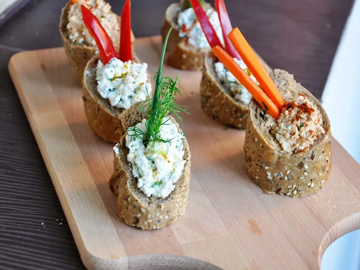 Leckere Dips zu Baguette: Frischk&auml;se-Variationen mit Kr&auml;utern, Paprika und Karottenstiften auf Vollkornbrot-Scheiben, garniert mit Dill.