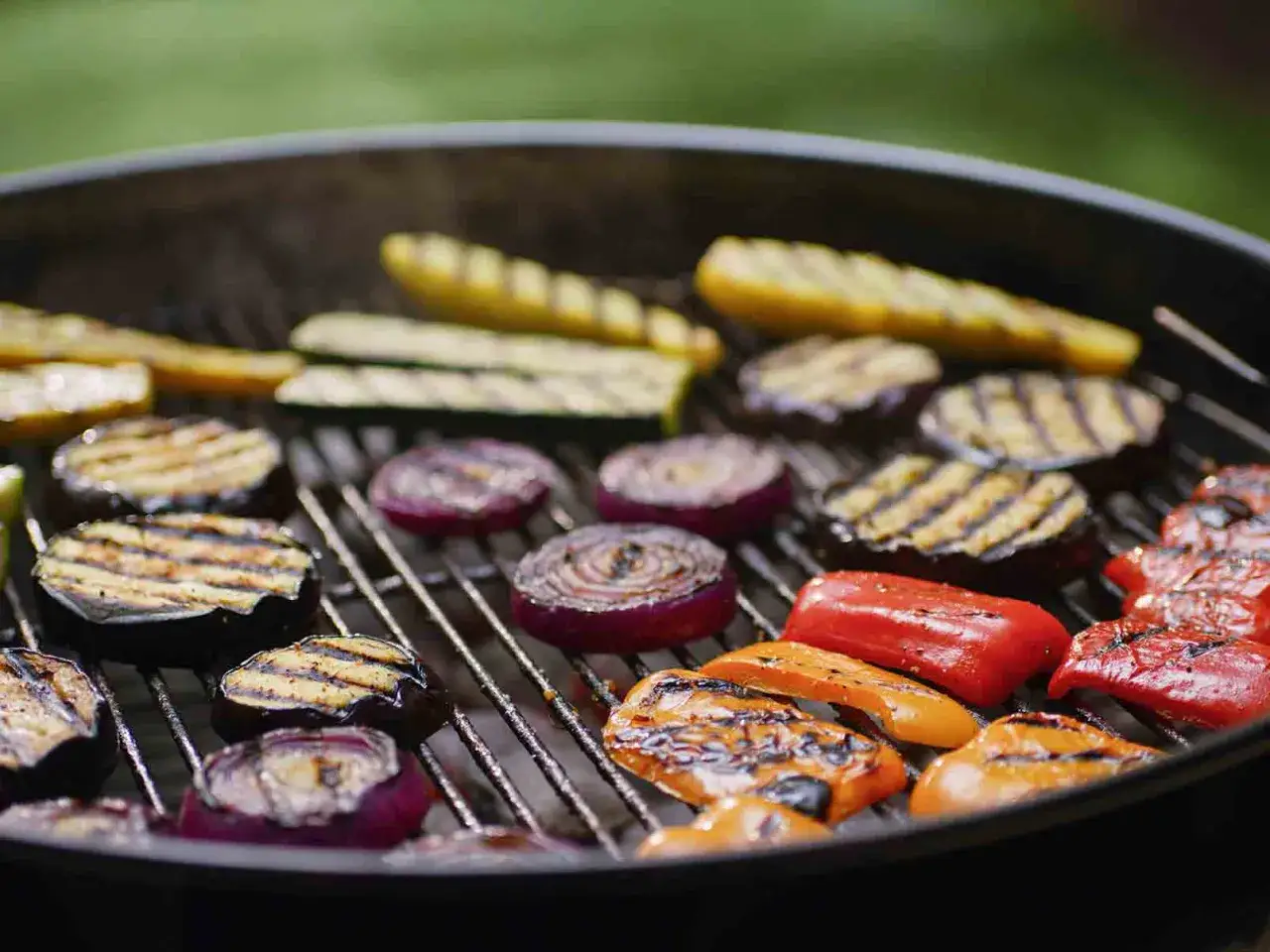 Leckeres Grillgemüse wie Zucchini, Auberginen, Paprika und Zwiebeln brutzeln auf einem Holzkohlegrill.