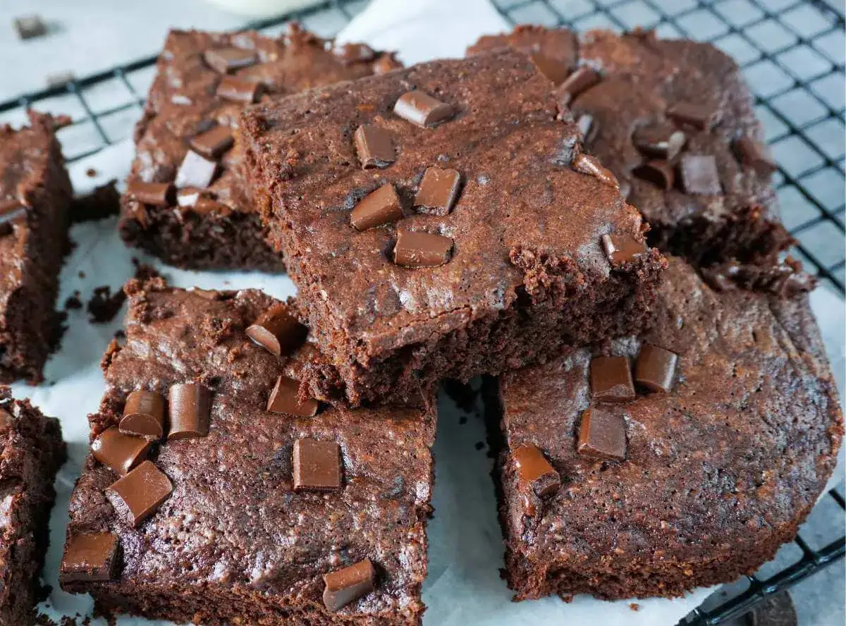 Saftige Zucchini Brownies mit Schokost&uuml;ckchen, auf einem Gitterrost arrangiert.