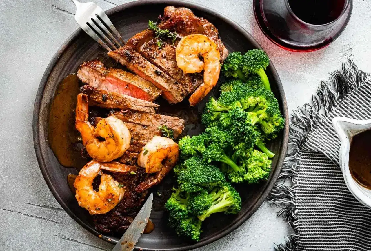 Ein k&ouml;stliches Surf and Turf Rezept: saftiges Steak, Garnelen und Brokkoli auf einem Teller.